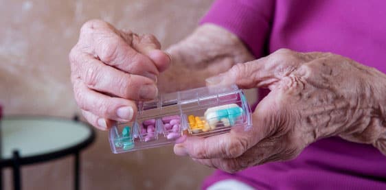 an image of an elderly person using a dosette box to organise their medications