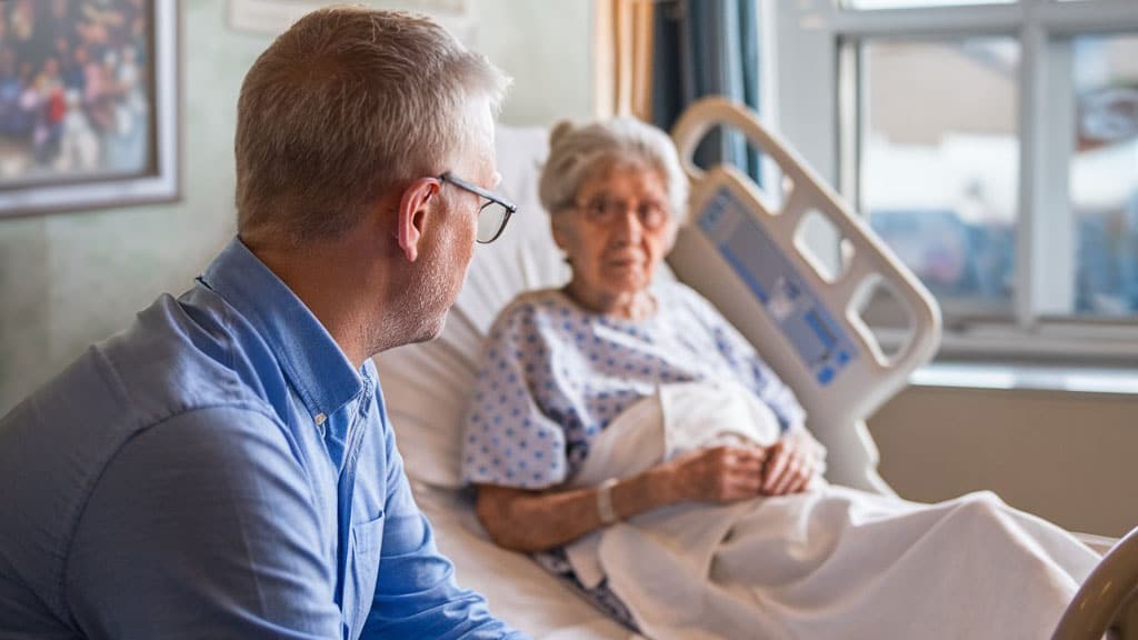 A son and mother sit together while she receives at home hospice care